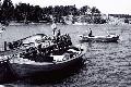 Sjösättning av en nybyggd båt, Ragnar Lindblom (Skomakars) stående på bryggan och Anselm Jansén (Södergrannas) sitter i båten på 1970-talet